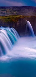 Blue waterfall cascading over rocky ledge in scenic natural landscape.