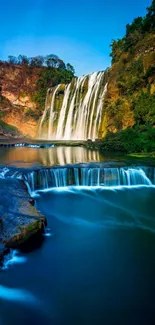 Beautiful waterfall in lush forest setting with blue sky.