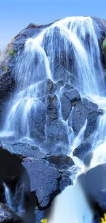 Stunning waterfall over rocky cliffs with clear blue sky.