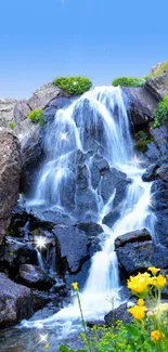 Waterfall with blue sky and flowers in a mobile wallpaper.