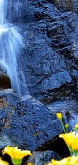 Cascading waterfall over rocks with yellow flowers in foreground.