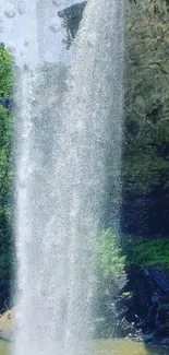 A refreshing waterfall cascading over rocks and greenery in this vibrant wallpaper.