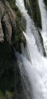 Captivating waterfall with lush greenery and flowing water on rocky cliff.