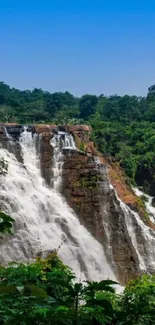 Stunning waterfall with lush green forest under a clear blue sky.