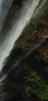 Majestic waterfall with lush green moss cascading down rocky cliff face.