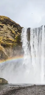 Majestic waterfall with a colorful rainbow in a serene natural setting.