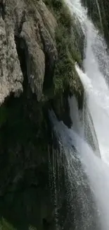 Majestic waterfall flowing over rocky cliff in nature scene.