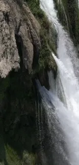 Majestic waterfall flowing down rugged rocks, perfect for a serene wallpaper.