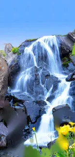 Serene waterfall flowing over rocks under a bright blue sky.