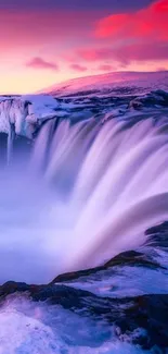 Vibrant waterfall under pink winter sunset sky.