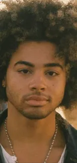 Close-up portrait of a person with a stylish afro hairstyle on a golden brown background.