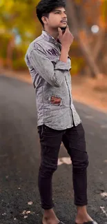 Stylish young man standing on a deserted street with autumn leaves in the background.