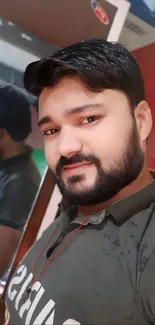 Man with beard taking a mirror selfie in stylish olive shirt.