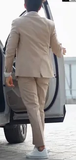 Person in beige suit exiting car in urban setting.