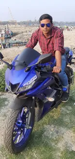 Stylish man on a blue motorcycle by the waterfront.