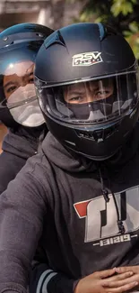 Two bikers on a motorcycle wearing sleek, stylish helmets.