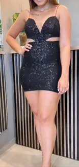 Person in a black sequin dress standing stylishly indoors.