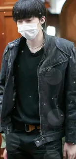 Person wearing a black leather jacket and white mask.