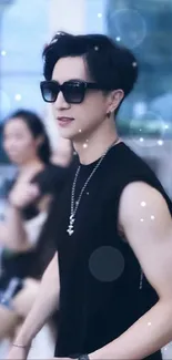 Stylish individual in black sleeveless outfit with sunglasses.