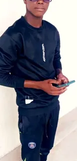 Person in black outfit holding a smartphone