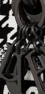 Black keychain with artistic pattern design on wallpaper.