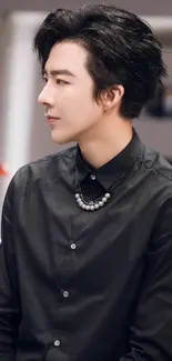 Person wearing a black shirt with stylish hair, looking sideways.