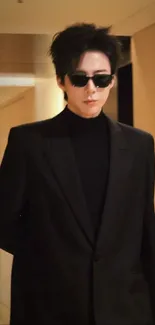 Man in black suit with sunglasses in a hallway.