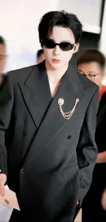 Person in a stylish black suit with accessories.