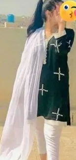 Woman in black attire with white dupatta against urban backdrop.