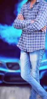 Man in plaid shirt and jeans standing before a sleek blue car.