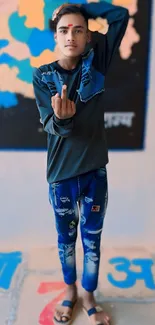 Young man in stylish blue jeans standing against colorful wall.