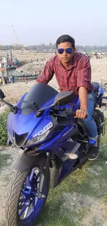 Man on blue motorcycle by the beach.