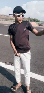 Boy posing for selfie on open road in casual outfit.