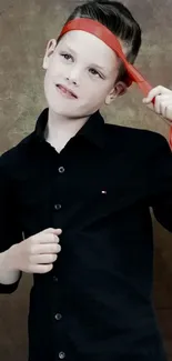 Boy in black shirt with red tie on rustic background.