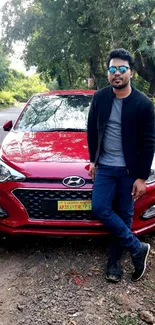 Person posing with a red car in nature.