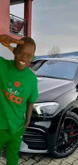 Man in green outfit posing with a sleek black car.