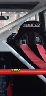 Racing car interior with Sparco seat and red seatbelts.