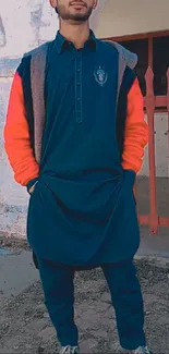 A person in a trendy navy and orange outfit against a rustic backdrop.