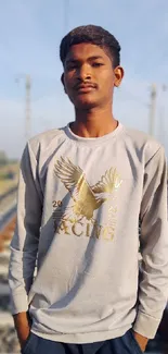 Portrait of a young man on railway tracks with scenic background.