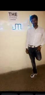 Man in stylish casual pose against beige background.