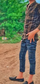 Stylish young man outdoors on a dirt path with green background.