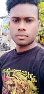 Young man in a black tee with urban outdoor background.