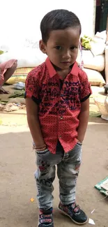 Young child in red shirt and jeans in a bustling outdoor market.