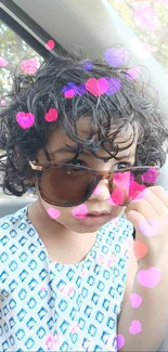 Child with sunglasses and curly hair in a car, stylish look.