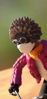 Clay art figure with a colorful jacket and goggles set against a vibrant background.