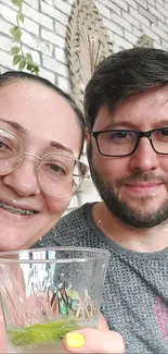 Couple smiling with a refreshing drink in a chic café setting.