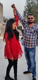 Fashionable couple posing on rooftop with city view.