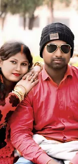 Stylish couple posing in red outfits with sunglasses.