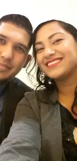 Stylish couple smiling and capturing a selfie together.