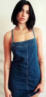 Fashionable woman in a denim dress on a cream backdrop.